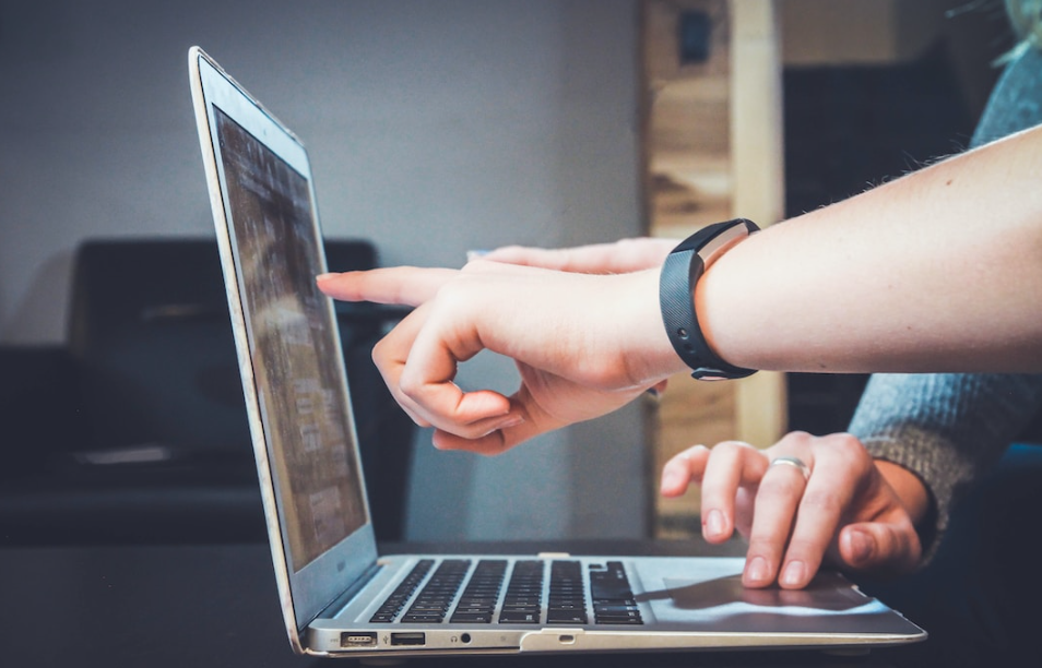 Two people pointing to a screen on a laptop reviewing their funnel chart for their marketing strategy